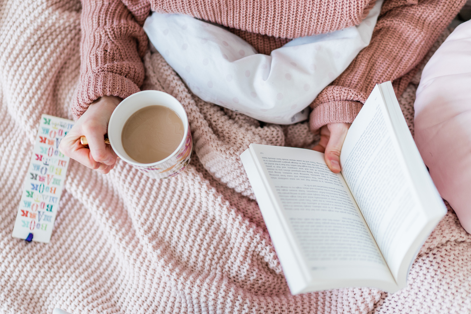 Woman Holding a Book and Cup of Coffee in Bed
